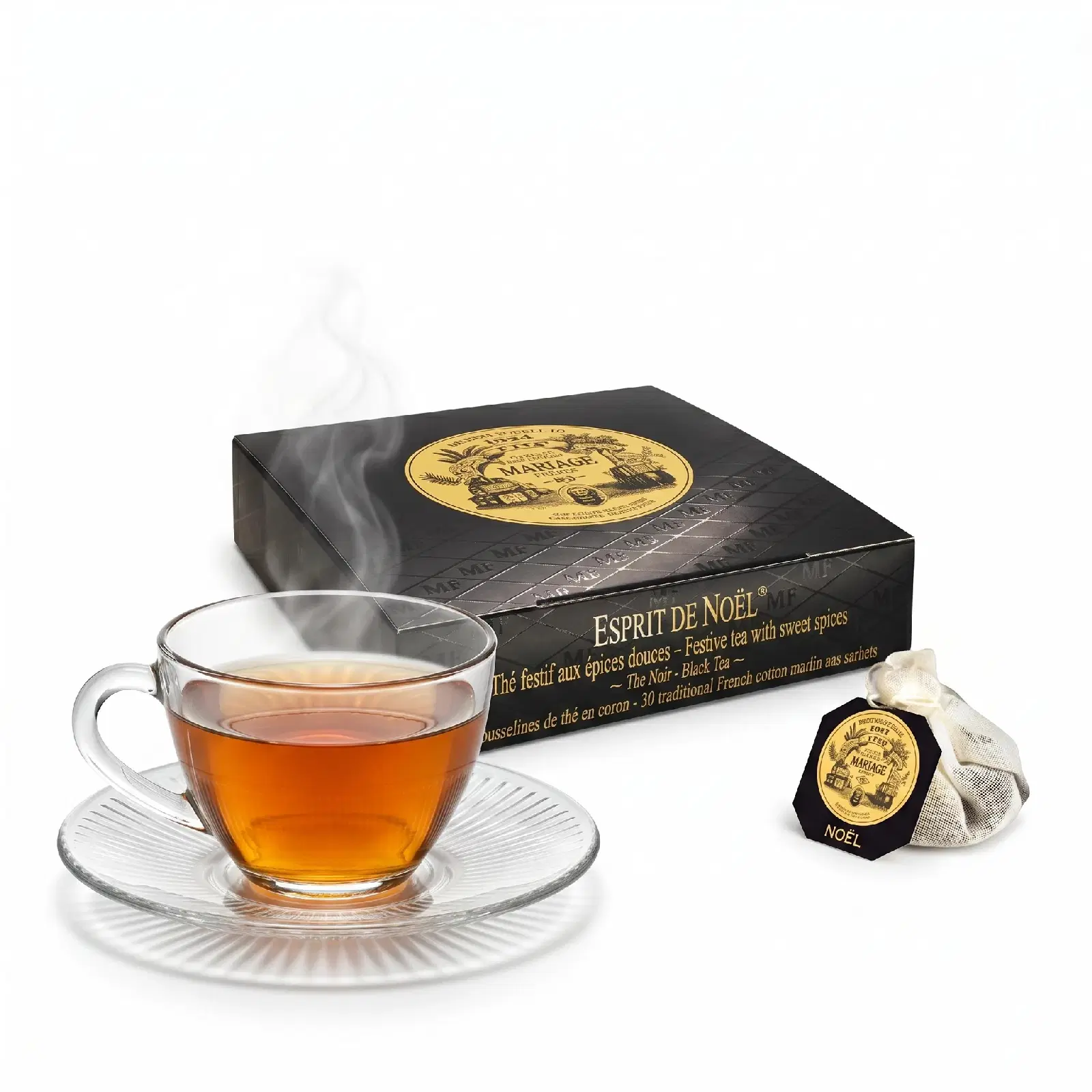 Une boîte noire de mousselines Esprit de Noël Mariage Frères, une tasse de thé fumante et une mousseline posée à côté