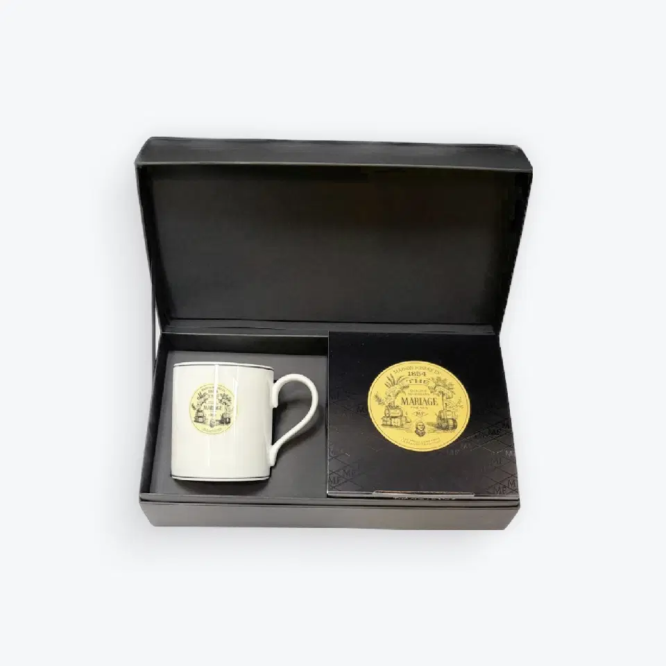 Coffret noir ouvert contenant un mug blanc Mariage Frères et une boîte noire de mousselines